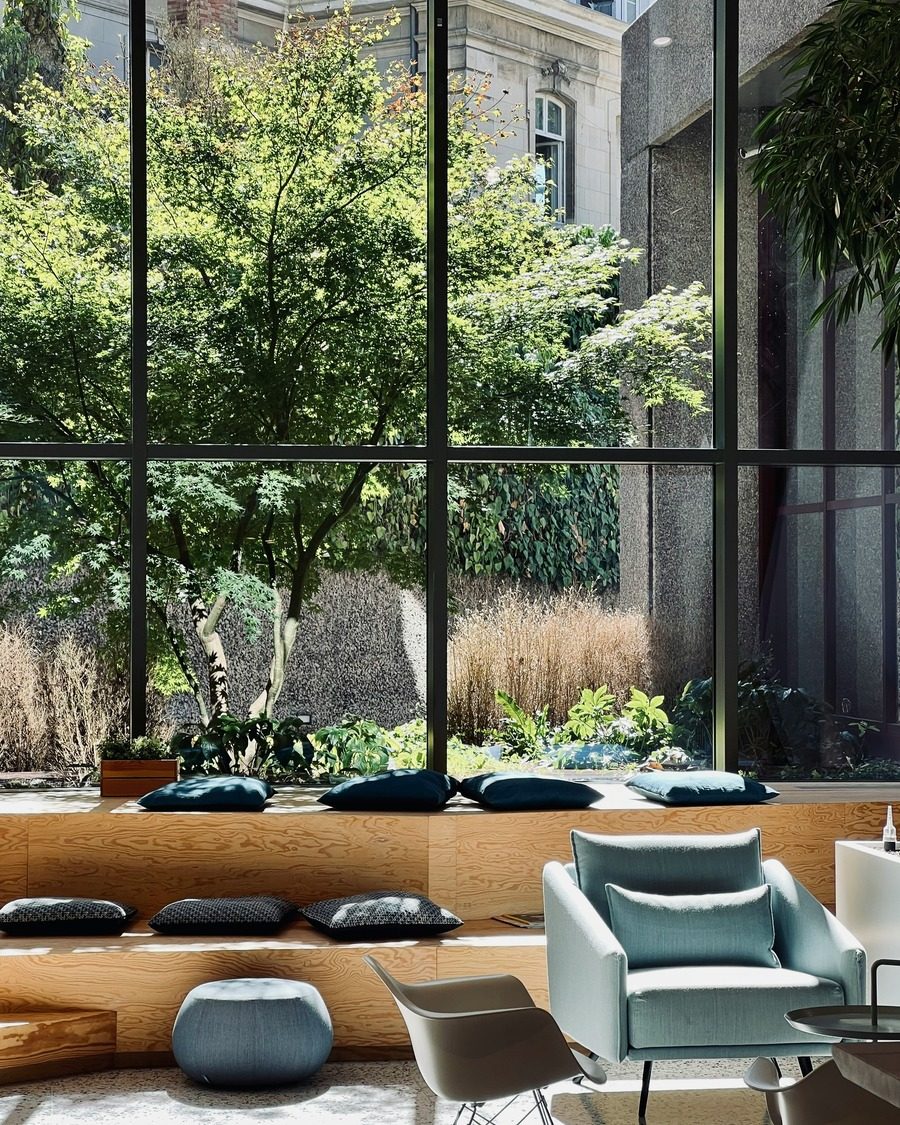 Salon vitré ouvert sur un jardin, lumière du jour.
